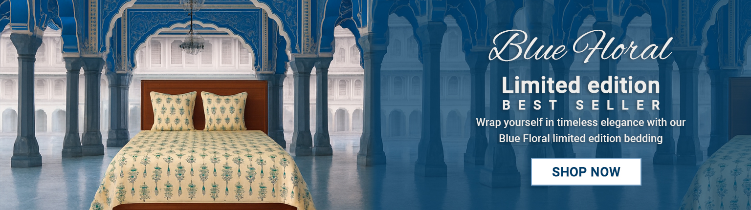 Blue Floral Limited Edition Bestseller Bedding – Shree Govindam Ethnic Studio Blue floral print cotton bedsheet set on a wooden bed against a traditional Jaipur-style blue arched interior background.